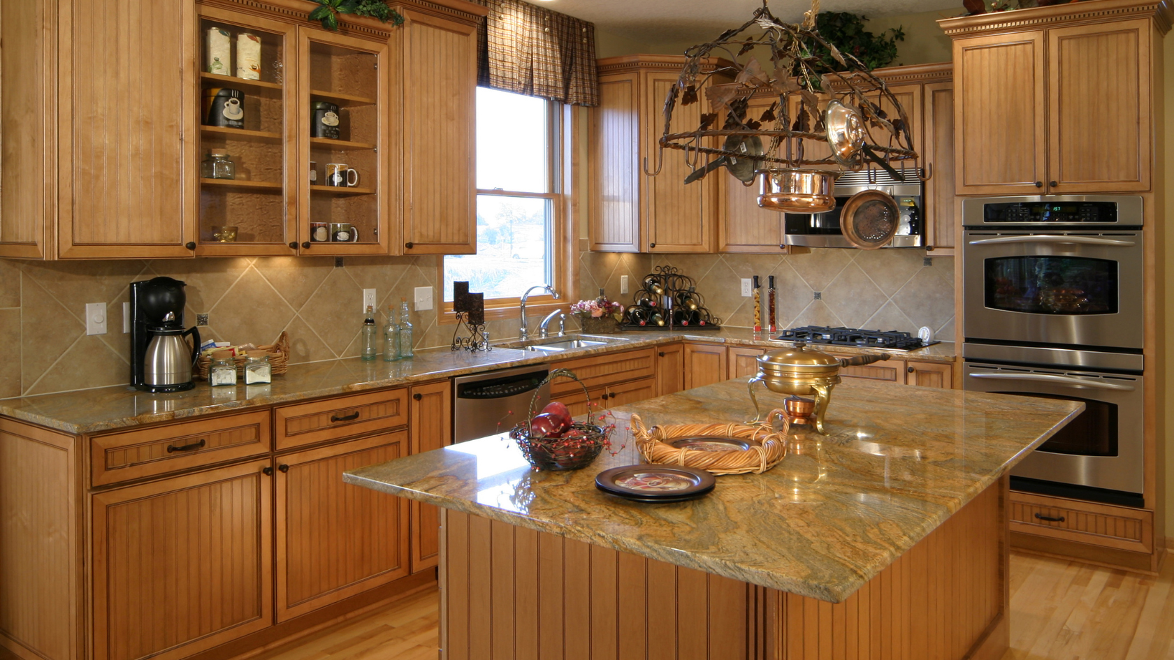Warm wooden kitchen with granite island, stainless appliances, and hanging pots